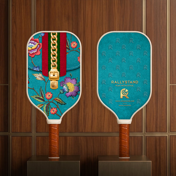 Front and back view of the Rally Stand premium floral and monogram print pickleball paddles showcased on luxury dark wood retail display stands.